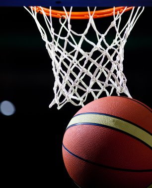Basketbol bir spor sahasında çemberin içinden geçiyor