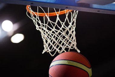 Basketbol bir spor sahasında çemberin içinden geçiyor
