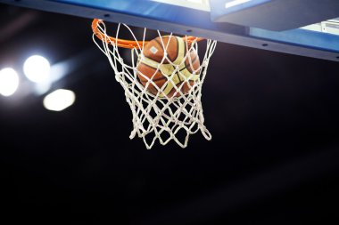 Basketbol bir spor sahasında çemberin içinden geçiyor