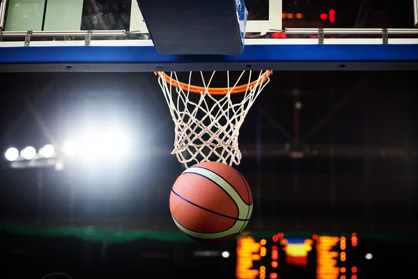 Баскетбол, що проходить через кільце на спортивній арені — стокове фото