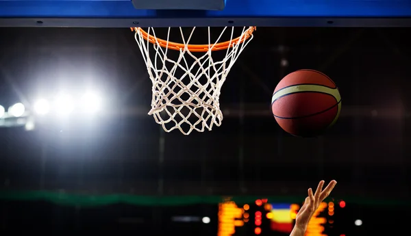 Basquete passando pelo aro em uma arena de esportes — Fotografia de Stock