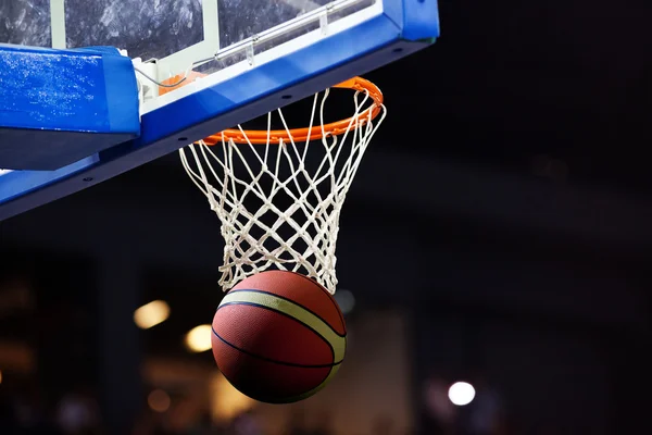 Basketbol bir spor sahasında çemberin içinden geçiyor