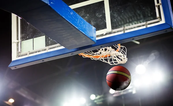 Basquete passando pelo aro em uma arena de esportes — Fotografia de Stock