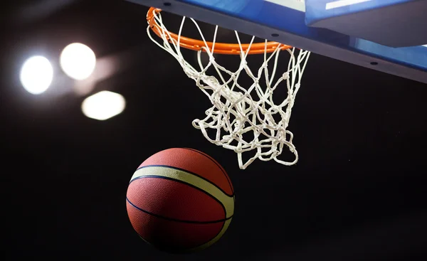 Basquete passando pelo aro em uma arena de esportes — Fotografia de Stock