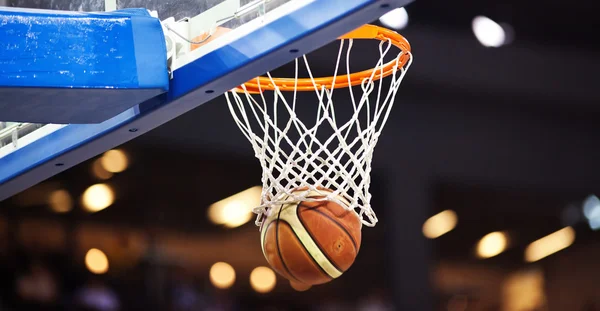 Basquete passando pelo aro em uma arena de esportes — Fotografia de Stock