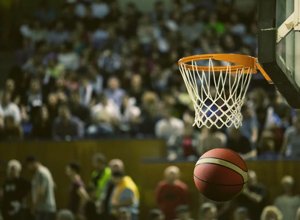 Basketbol bir spor sahasında çemberin içinden geçiyor