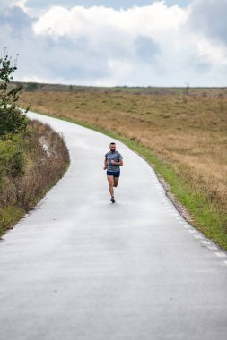 Genç adam köy yolunda koşuyor.
