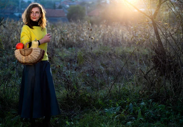 在秋天的花园里提着装满南瓜的篮子的女人 — 图库照片