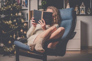 Evdeki rahat Noel zamanı kitap okuyan bir kadın.