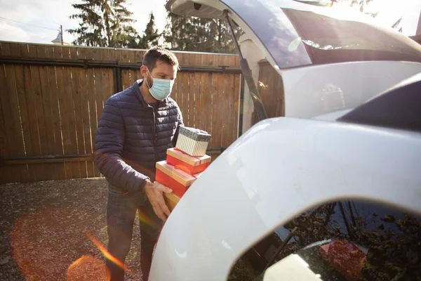 man packing Christmas gift boxes in car