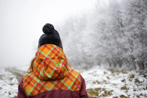 戴着帽子在冰雪覆盖的森林里行走的女人 — 图库照片