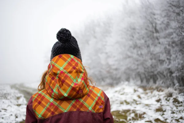 戴着帽子在冰雪覆盖的森林里行走的女人 — 图库照片