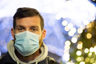Noel ışıklarında maske takan bir adam.