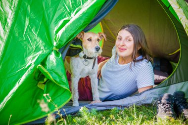Dağlarda sevimli teriyer köpeğiyle kamp yapan bir kadın.