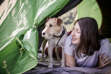 Dağlarda sevimli teriyer köpeğiyle kamp yapan bir kadın.