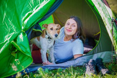 Dağlarda sevimli teriyer köpeğiyle kamp yapan bir kadın.
