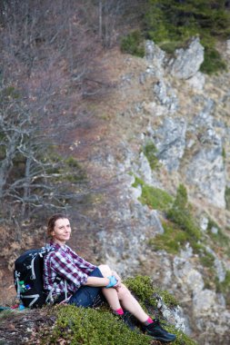 Dağın tepesinde oturmuş manzaraya hayran olan bir bayan yürüyüşçü.