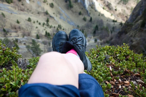 woman's feet in hiking boots sitting on top of mountain