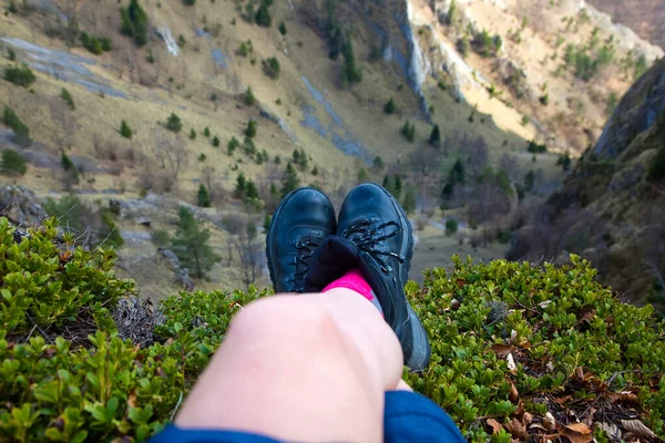 woman's feet in hiking boots sitting on top of mountain