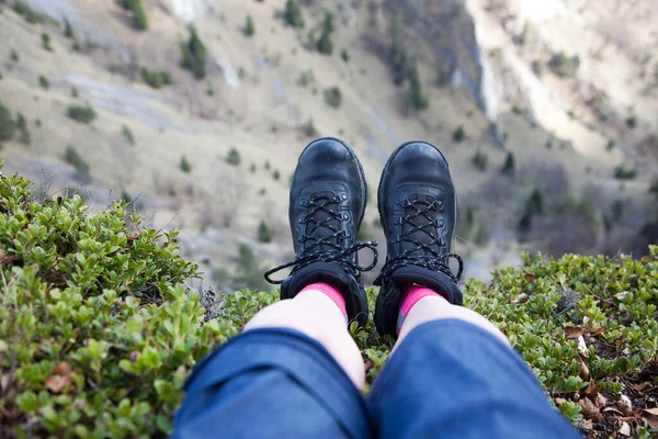 woman\'s feet in hiking boots sitting on top of mountain