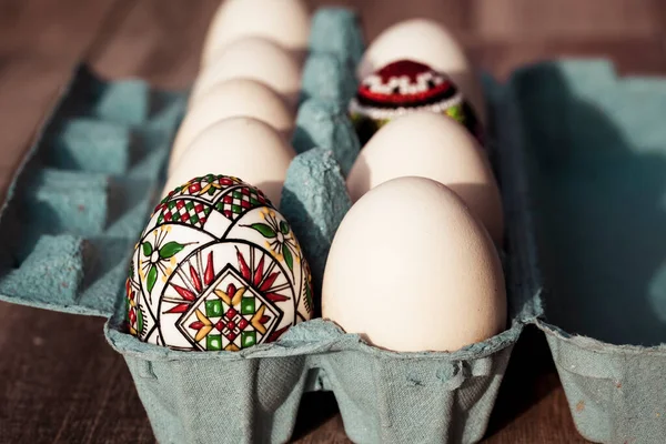 white eggs in box and traditional painted easter eggs from Bucovina region, Romania