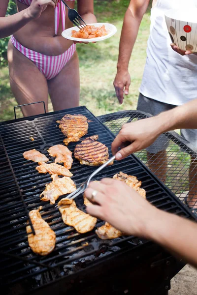 Arka bahçede barbekü yapıyor.