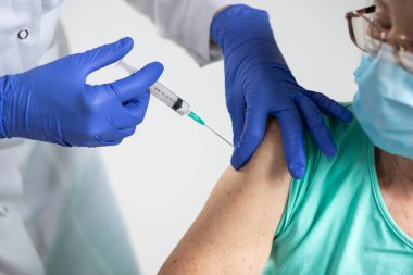 Yaşlı bir kadın koronavirüs aşısı oluyor.