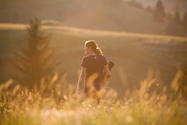Parkta yürüyen kameralı genç bir kadın.