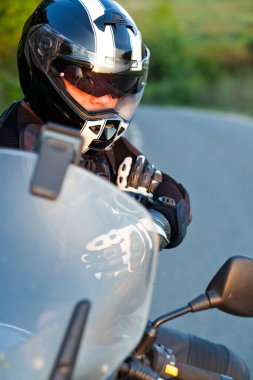 Motosikletli bir sürücü manzaranın tadını çıkarmak için ara veriyor. Motosikletli bir yaz gezisi.