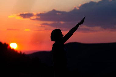 Sahilde kameralı bir kadının silueti.