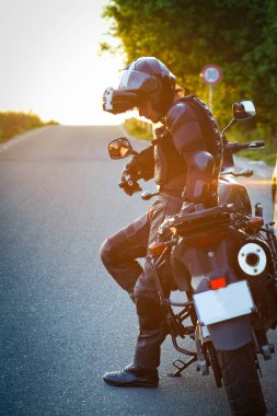 Motosikletli bir sürücü manzaranın tadını çıkarmak için ara veriyor. Motosikletli bir yaz gezisi.