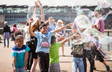 Çocuklar şehirde sabun köpüğüyle oynuyorlar.