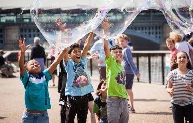 Çocuklar şehirde sabun köpüğüyle oynuyorlar.