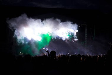 Parlak sahne ışıklarının önünde tezahürat yapan kalabalık.