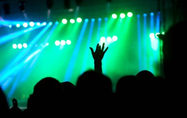 Parlak sahne ışıklarının önünde tezahürat yapan kalabalık.