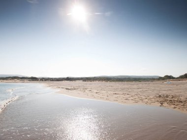 Gün ortasında kumlu sahilde el salla 