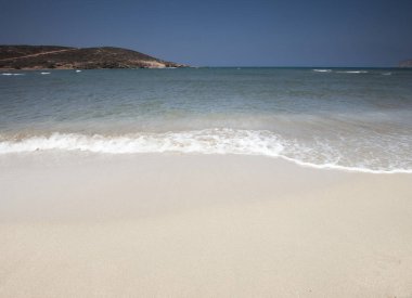 Gün ortasında kumlu sahilde el salla 