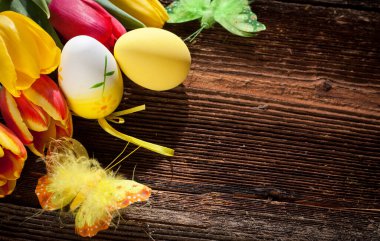 Paskalya yumurtaları ve yıpranmış ahşap arka planda taze bahar laleleri.