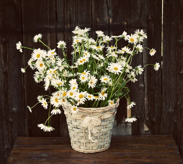 bouquet of daisies in a vase on a wooden background