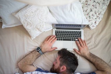 Evde dizüstü bilgisayarı olan bir adam var.