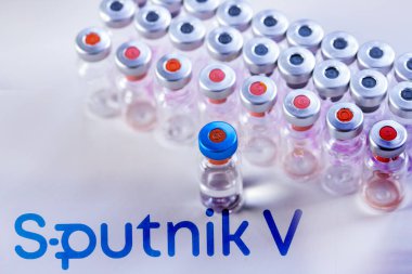 CLUJ-NAPOCA -ROMANIA - 9 Mart 2021: Sputnik Aşısı Covid-19 konsepti. Şırınga iğnesi ve aşı, arka planda bulanık Sputnik V şirket logosu..
