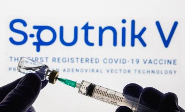 CLUJ-NAPOCA -ROMANIA - 9 Mart 2021: Sputnik Aşısı Covid-19 konsepti. Şırınga iğnesi ve aşı, arka planda bulanık Sputnik V şirket logosu..