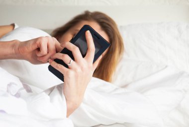 Yatakta akıllı telefon kullanan güzel bir kadın