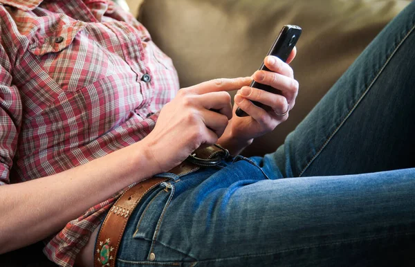 mid adult woman relaxing on sofa and browsing on smartphone