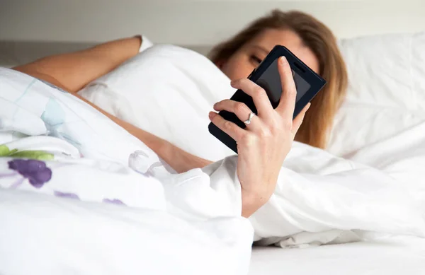 beautiful woman using smartphone in bed
