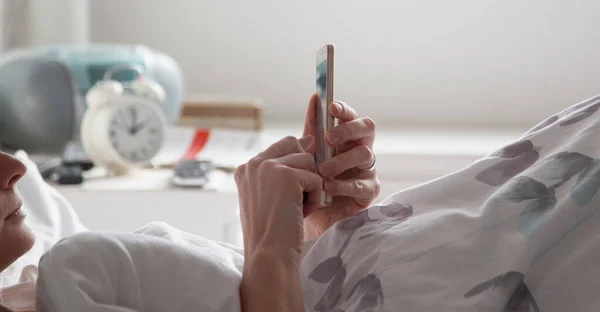 woman using smartphone in bed