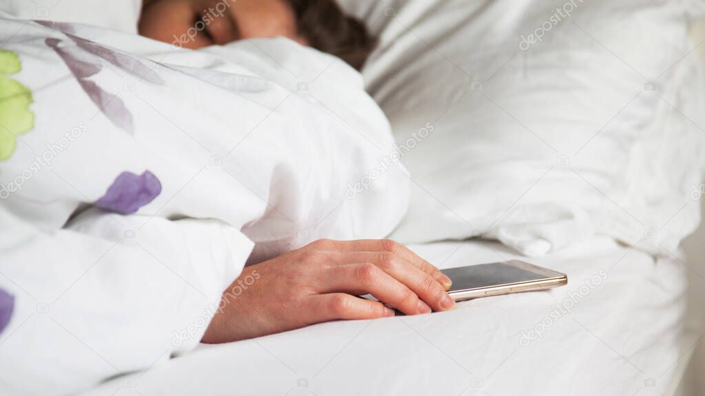 woman sleeping in bed being woken by mobile phone