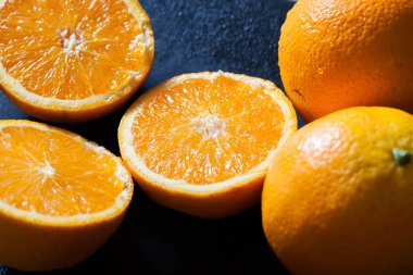 taze organik portakallar ve siyah arka planda meyve suyu.