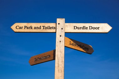 Lulworth Koyu ve Durdle Kapısı. Güzel gökyüzü olan tahta tabela.