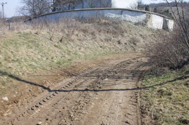 Terk edilmiş bir arabanın toprak yolu ve çakıl izleri, kırsal alan.